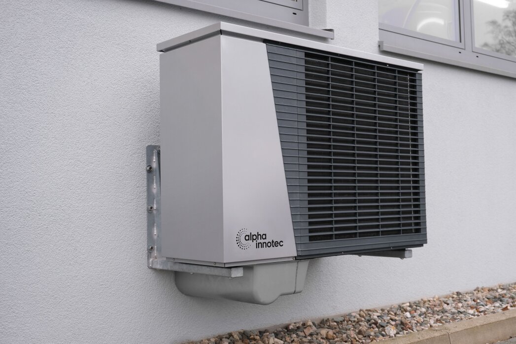 Einfamilienhaus mit Außeneinheit einer Wärmepumpe im Garten